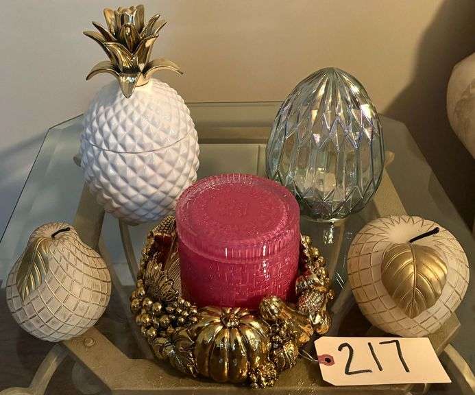 TABLETOP DECOR LOT: LIDDED WHITE AND GOLD PINEAPPLE, LARGE GOLDEN CIRCULAR CANDLEHOLDER WITH CANDLE IN LIDDED GLASS JAR, WHITE AND GOLD-TONE APPLE AND PEAR, GLASS EGG SHAPED FACETED LANTERN image