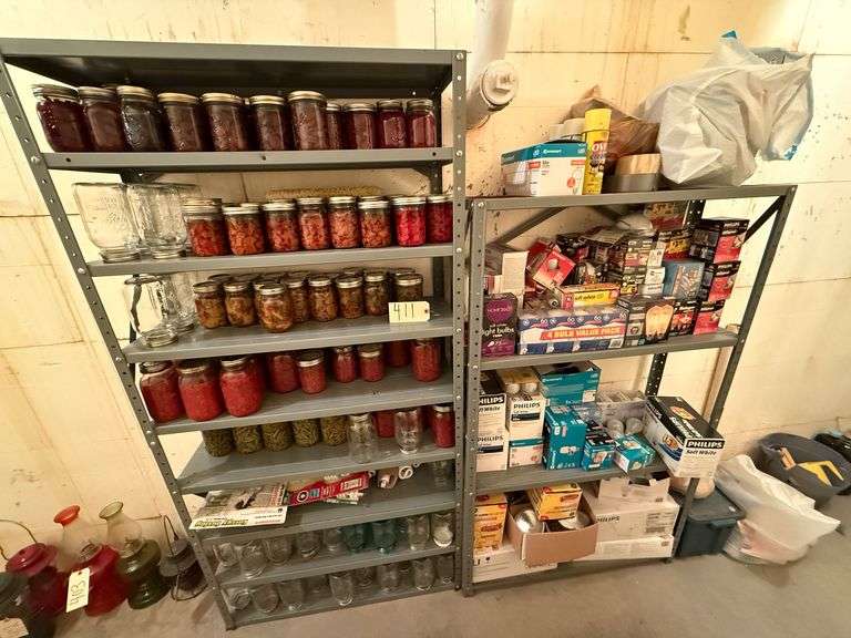 PAIR OF METAL SHELVES, ONE IN GOOD SHAPE, ONE SHOWING SOME RUST ON THE TOP SHELF - MULTIPLE CANNING JARS, SOME WITH FOOD IN THEM, SOME EMPTY - BLUE BALL PERFECT MASON JARS - OTHER SHELF HAS CHOCK-FULL OF LIGHTBULBS OF ALL SHAPES AND SIZES image