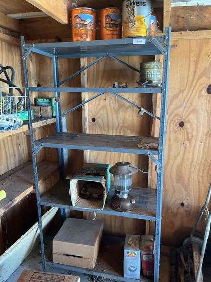 Metal shelf and contents, including Coleman oil lamp, grill rocks, paint image