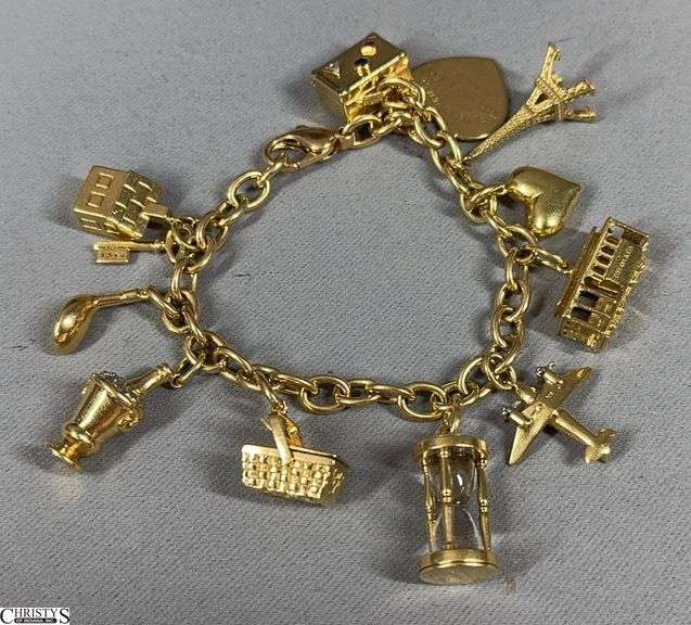 Tiffany & Co. Gold Charm Bracelet.  weight 97.1 grams,  The bracelet is marked 18K.  Both heart shapes marked Tiffany & Co., the small heart includes 5 small diamonds.  The airplane is marked 750.  Others marked Tiffany are the house with a small diamond, train car, hourglass (also marked 750), key, champagne bucket image