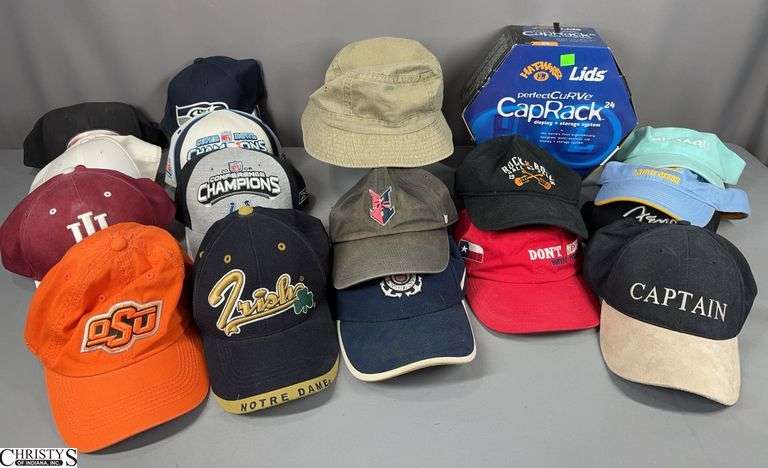 16 Ball Caps,  1 Khaki Colored Bucket Hat and a Lids Perfect Curve Cap Rack Display/Storage Rack.  All the items are in a white laundry basket. image