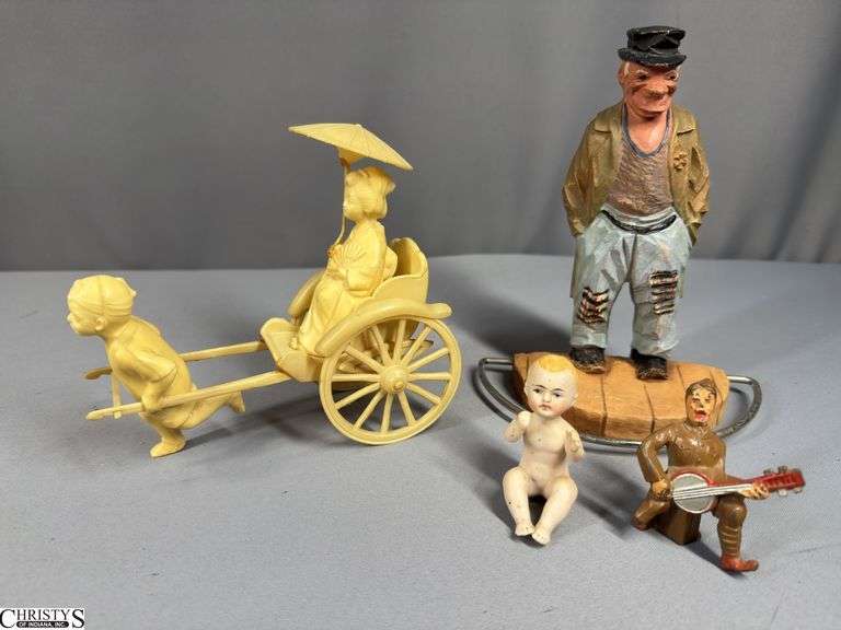 Miniature Celluloid Plastic Rickshaw with Figure Pulling a Passenger.  Wheels are movable.  The umbrella needs repair.  Also includes a 2 1/2" Bisque Baby Figure, a 2 1/2" Manoil Toy Soldier Playing a Banjo, and a 7 1/2" Tall Clown Hobo Figure image