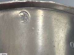 2 Pewter Tankards. Both Marked 'Quart' And Feature A Decorative Handle. One Mug Has GR 329 10 Stamped On It, And The Other Mug Has 1910 Stamped On It.