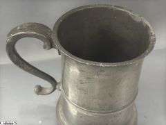 2 Pewter Tankards. Both Marked 'Quart' And Feature A Decorative Handle. One Mug Has GR 329 10 Stamped On It, And The Other Mug Has 1910 Stamped On It.