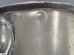 2 Pewter Tankards. Both Marked 'Quart' And Feature A Decorative Handle. One Mug Has GR 329 10 Stamped On It, And The Other Mug Has 1910 Stamped On It.