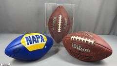 3 Footballs- One Blue NAPA Auto Parts and 2 Wilson National Football League.  One Wilson has autographed but they are fading and can not be read.  The other Wilson ball is in a display case.