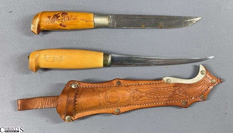 2 Fixed Blade Knives with Wood Handles.  One has a Sheath,  the "Rapala" Fish Log, the "Finland" Marking on the Handle and 10 1/2" Total Length.  The other knife is approx. 10" in Total Length and has a Moose Design Handle. image