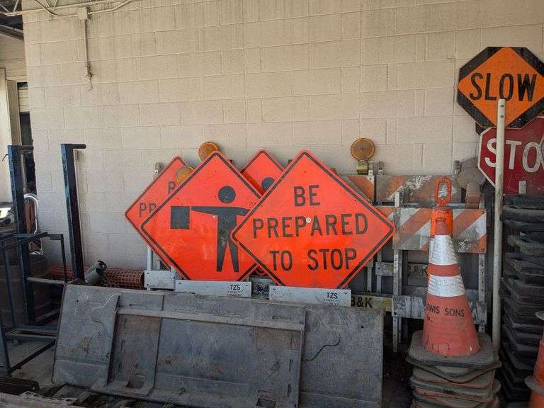 Traffic control cones, signs, and roll of orange plastic barrier
