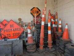 Traffic control cones, signs, and roll of orange plastic barrier