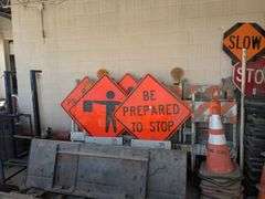 Traffic control cones, signs, and roll of orange plastic barrier