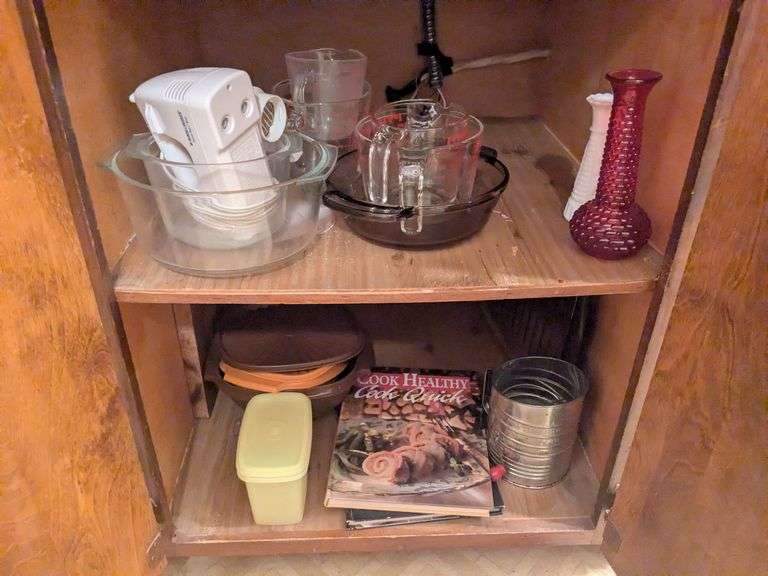 Bottom 2 shelves: 4 Pyrex measruing cups, glass mixing bowls, glass baking dish, 2 vases, tupperware storage containers and misc. image