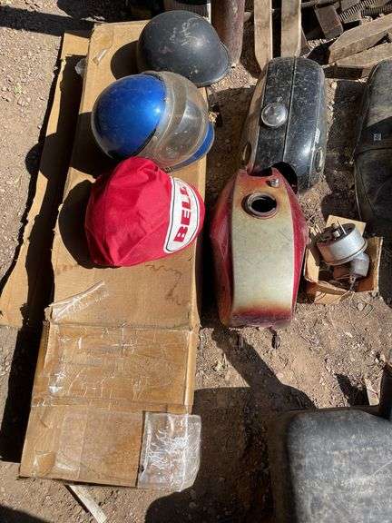 Lot of motorcycle parts. Lights tanks, helmets, and exhaust.
