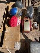 Lot of motorcycle parts. Lights tanks, helmets, and exhaust.
