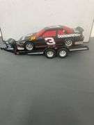 die-cast model of Dale Earnhardt's #3 Goodwrench NASCAR Lumina, which appears to be a 1:24 scale model, and it is depicted with a flatbed trailer.