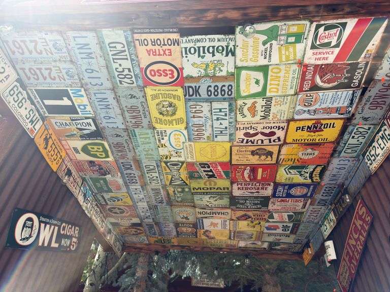 Huge lot! Of license plates/ replica vintage advertising signs. Everything on the under side of the entryway cieling image