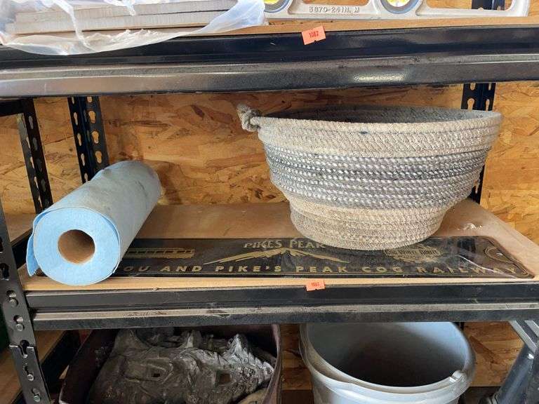 Contents of third shelf. Rope basket, roll of towels and pikes Peak sign. image